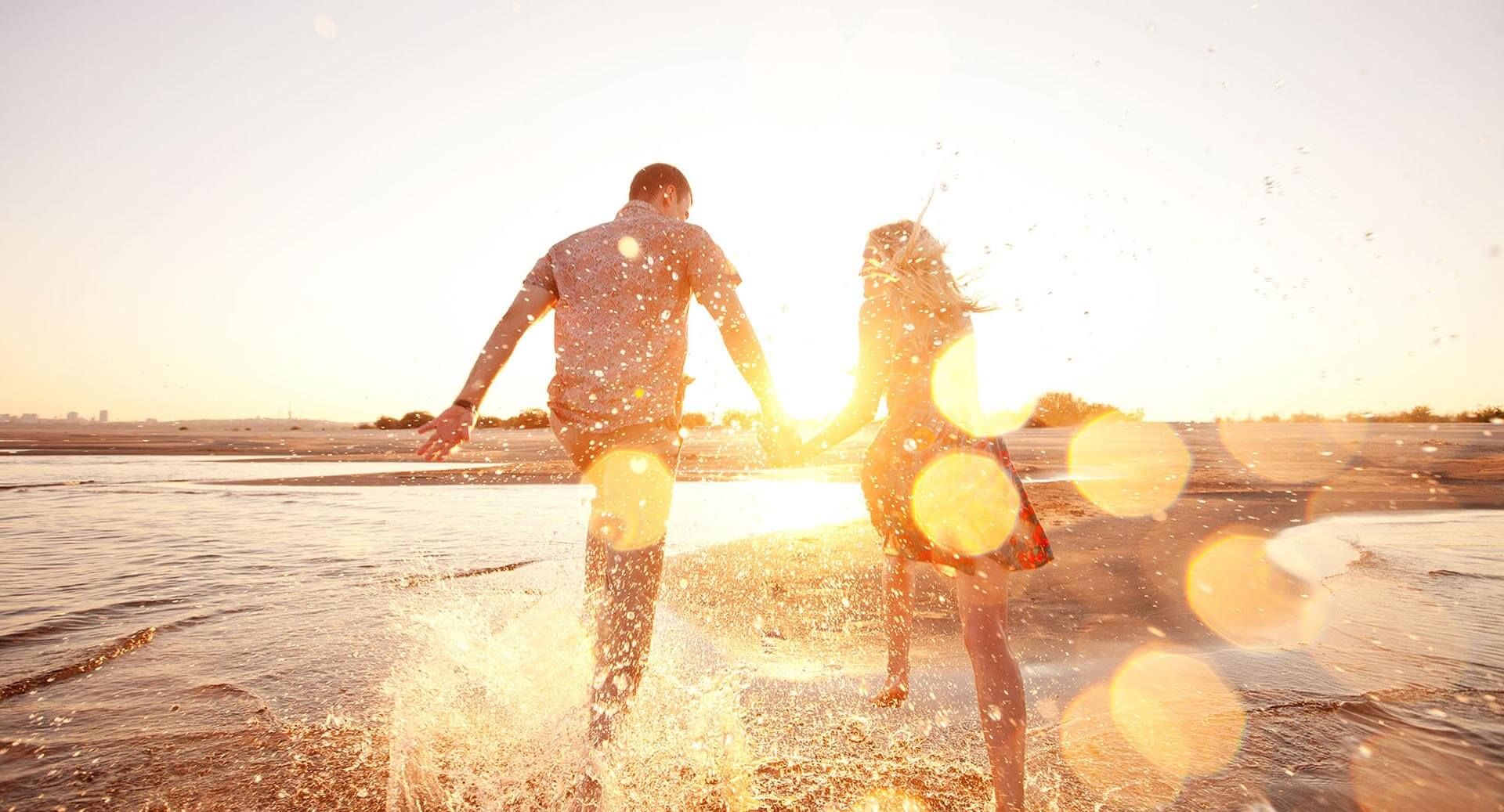 Happy couple walkinig in shallow water on the beach